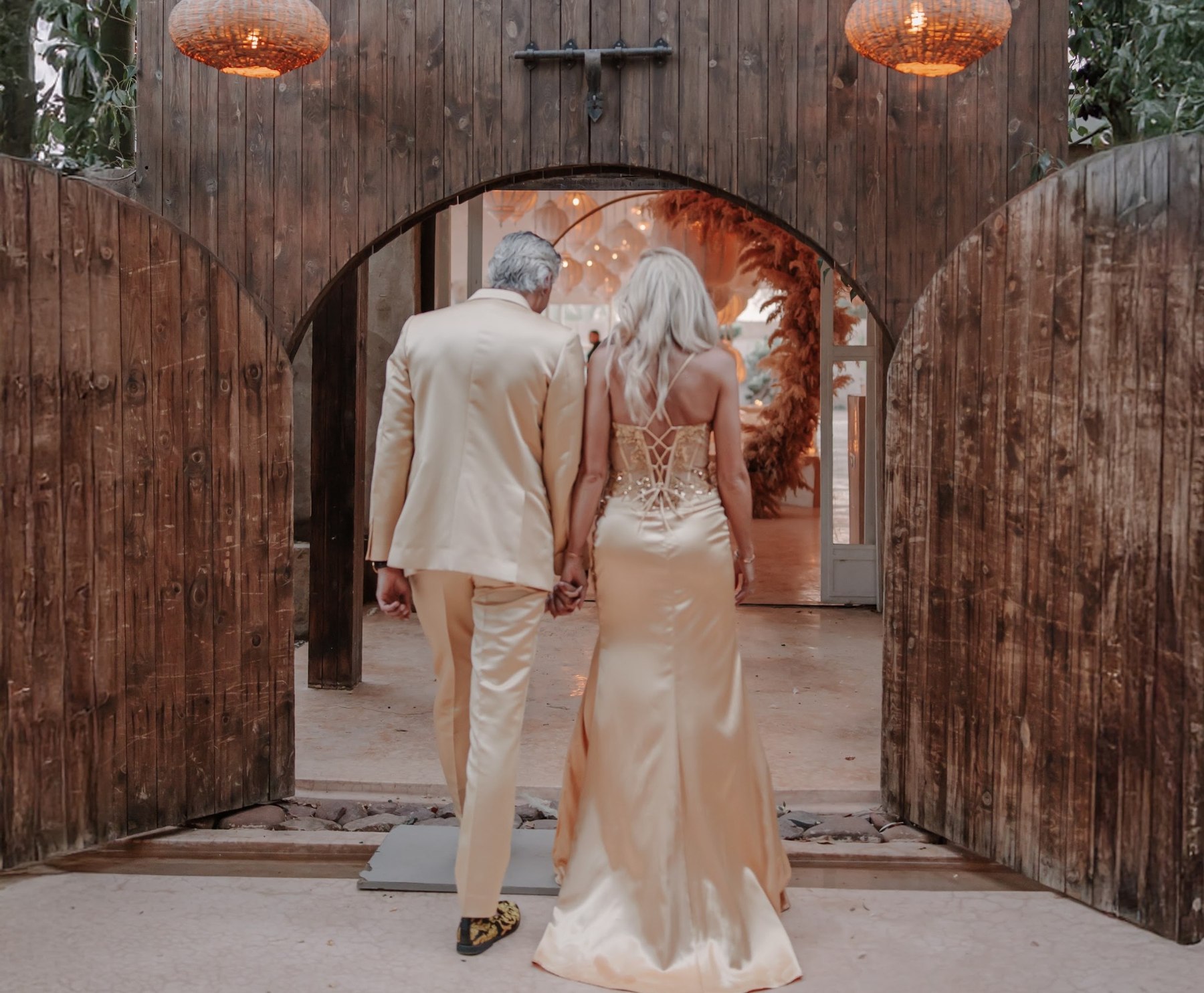 Couple walking into their celebration through wooden doors